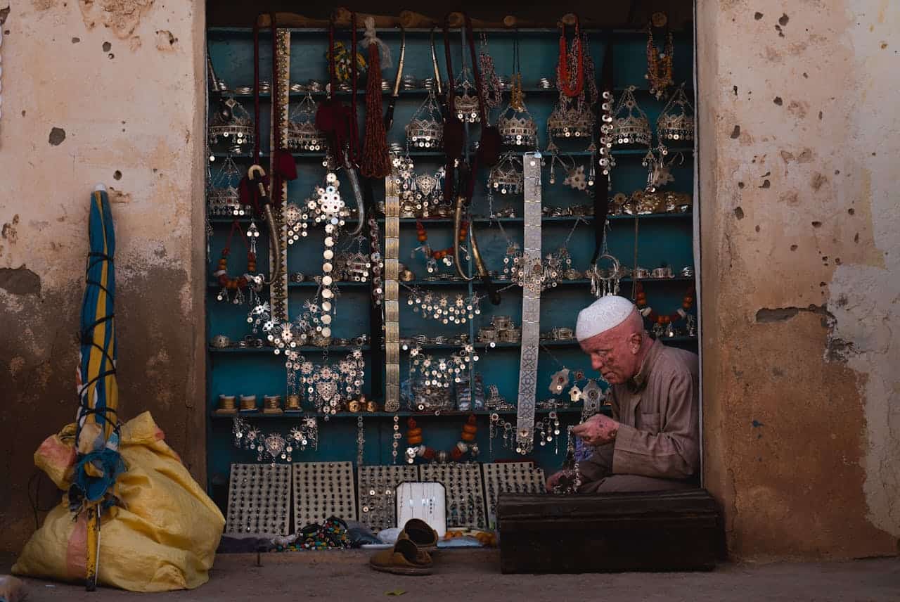 A senior man sells handcrafted jewelry at a market in Tiznit, Morocco.